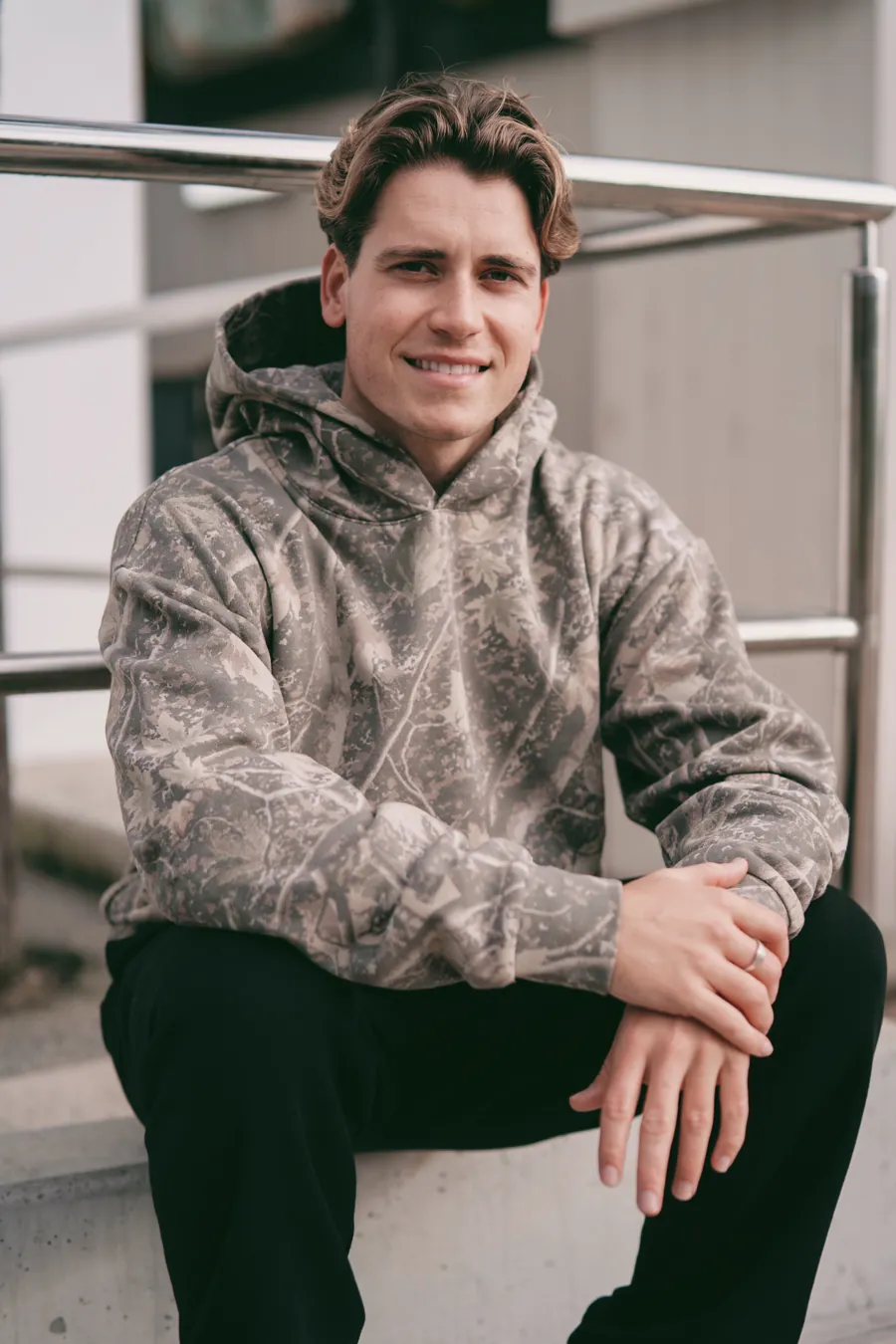 Man in a Deadwood Camo Heavyweight hoodie, seated